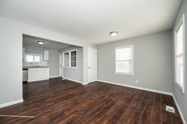 unfurnished living room with dark wood-type flooring, plenty of natural light, and sink