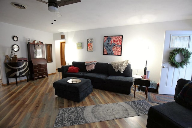 living room featuring dark wood-type flooring and ceiling fan