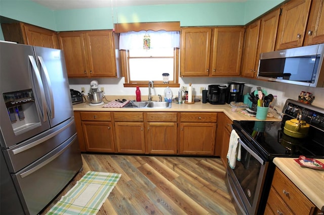 kitchen with sink, light wood-type flooring, and appliances with stainless steel finishes