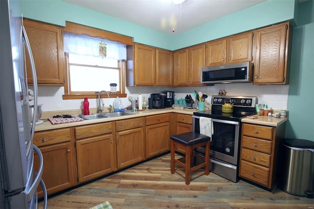 kitchen featuring stainless steel appliances, tasteful backsplash, sink, and light hardwood / wood-style floors