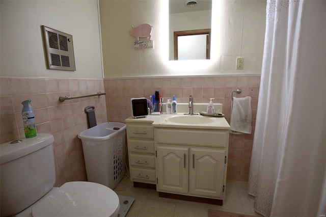 bathroom with vanity, toilet, tile patterned flooring, and tile walls