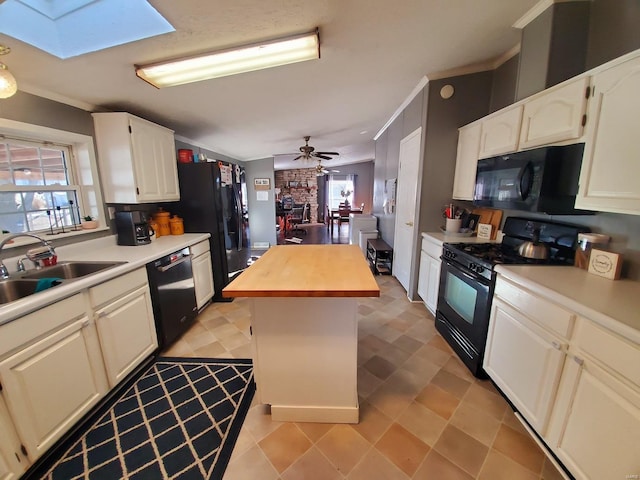 kitchen with black appliances, a kitchen island, a skylight, sink, and ceiling fan