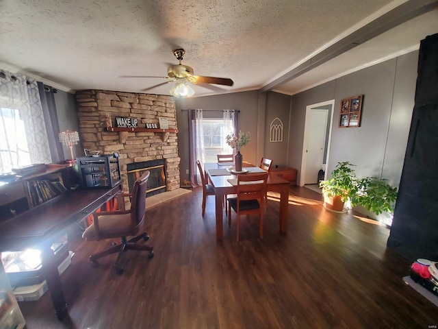 dining room with a textured ceiling, dark hardwood / wood-style flooring, ornamental molding, and a stone fireplace