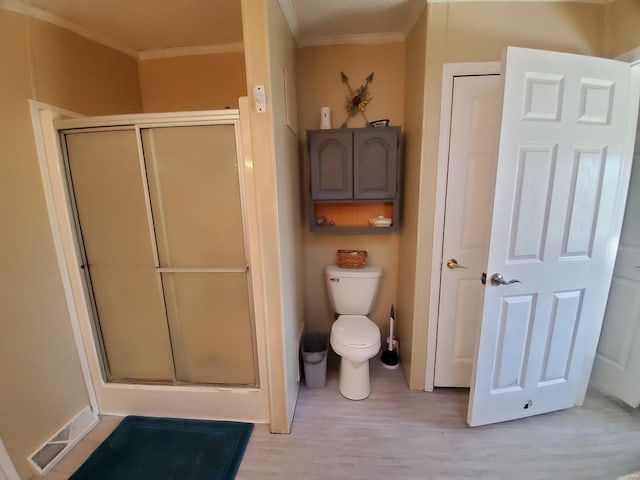 bathroom with wood-type flooring, toilet, walk in shower, and ornamental molding