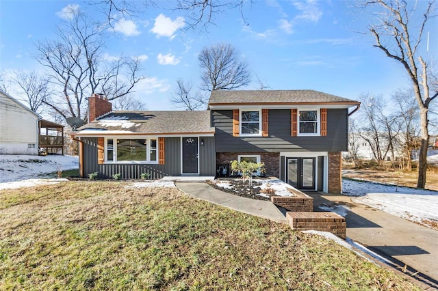 tri-level home with a front yard, board and batten siding, and a chimney