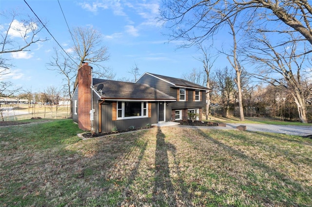 split level home featuring a chimney and a front lawn