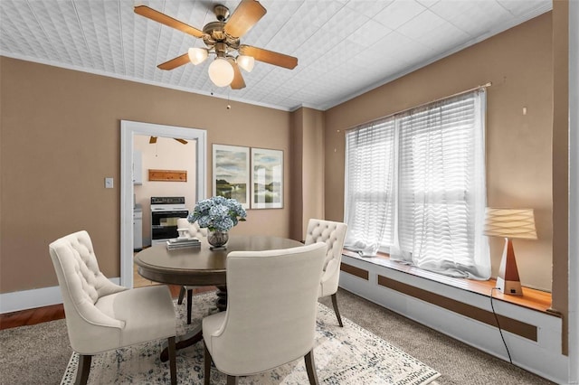 carpeted dining room with ceiling fan and crown molding