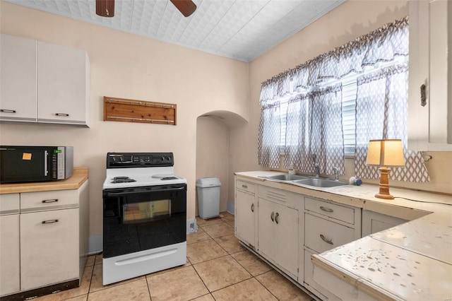 kitchen featuring light tile patterned floors, white cabinetry, range with electric stovetop, ceiling fan, and sink