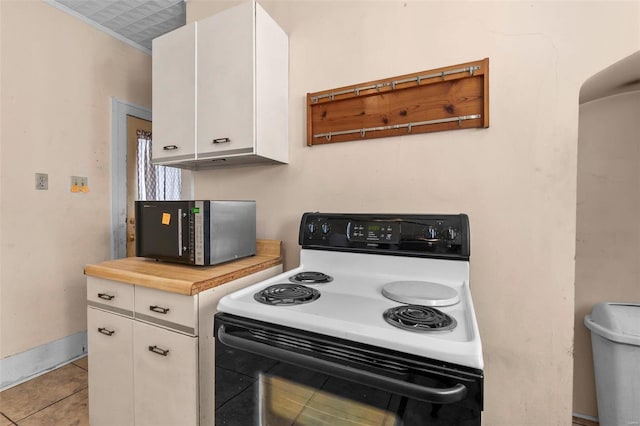 kitchen with white cabinetry, electric range, ornamental molding, and light tile patterned flooring