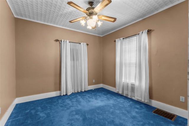 spare room featuring ceiling fan, dark carpet, and ornamental molding