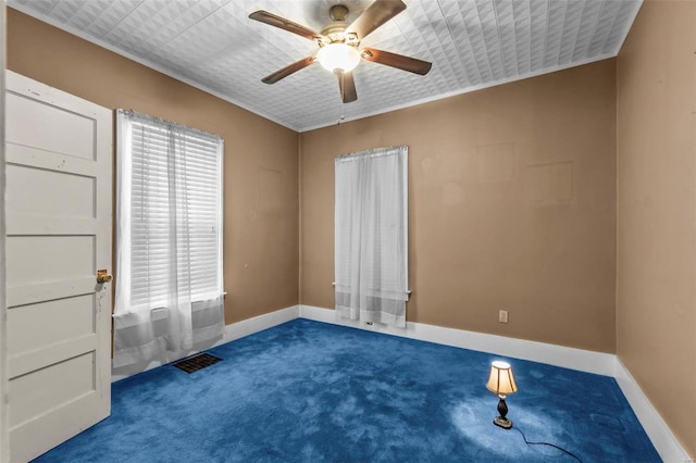 unfurnished room featuring dark colored carpet, ornamental molding, and ceiling fan