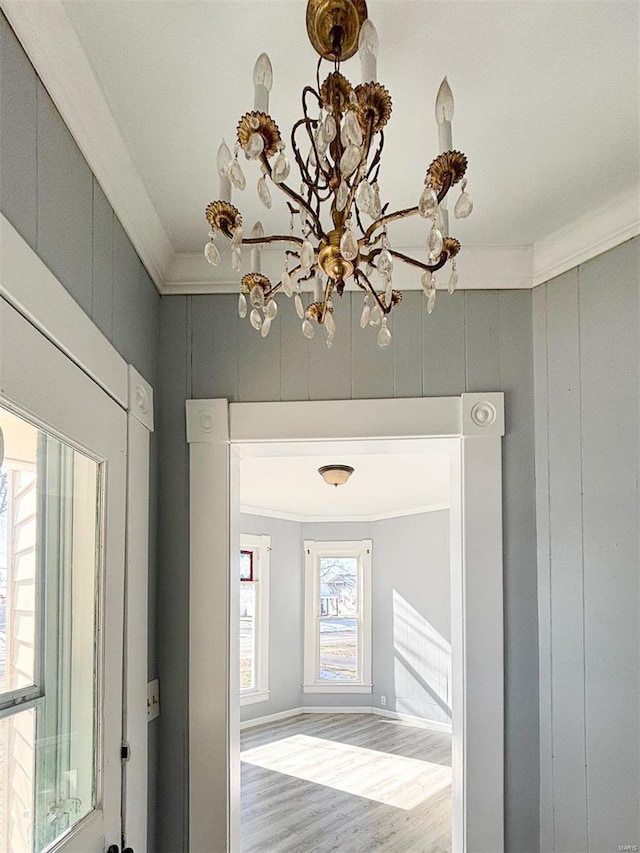 hall with a chandelier, crown molding, and wood-type flooring