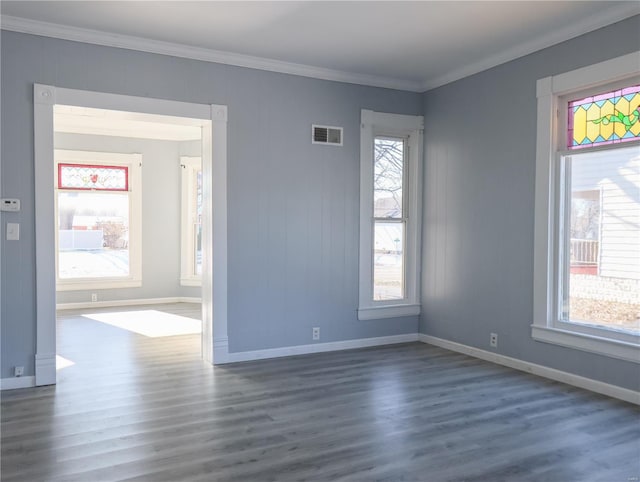 spare room featuring a healthy amount of sunlight, ornamental molding, and dark wood-type flooring