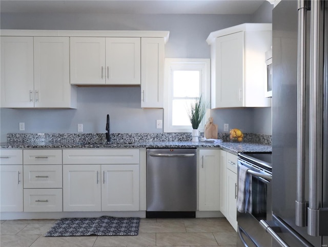 kitchen featuring light stone counters, white cabinets, appliances with stainless steel finishes, and sink