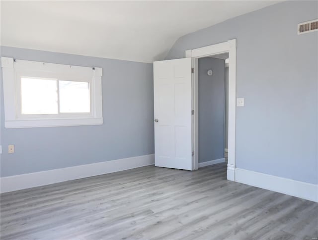 unfurnished room featuring light wood-type flooring and vaulted ceiling