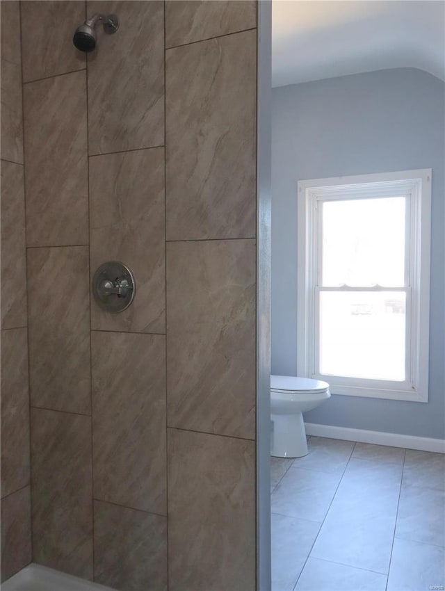 bathroom featuring toilet, a tile shower, and tile patterned flooring