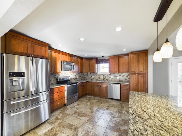 kitchen featuring sink, appliances with stainless steel finishes, light stone countertops, decorative backsplash, and decorative light fixtures