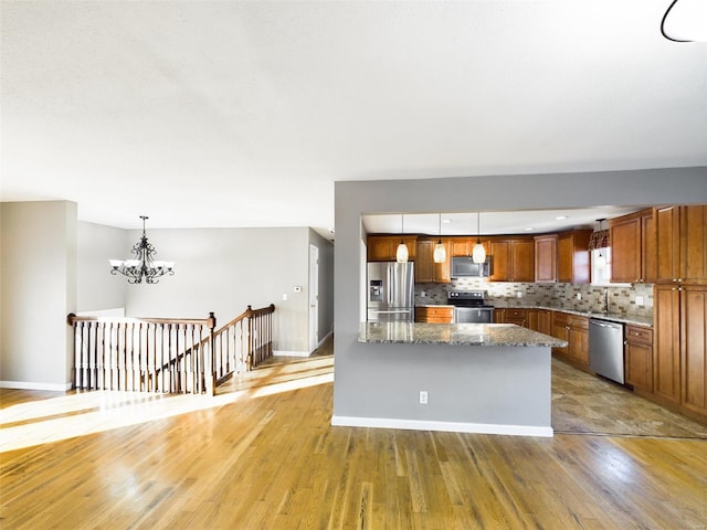 kitchen with wood-type flooring, appliances with stainless steel finishes, pendant lighting, and decorative backsplash