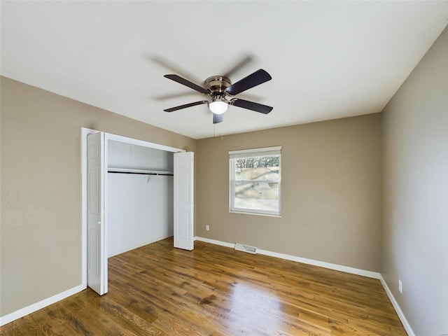 unfurnished bedroom featuring dark wood-type flooring, a closet, and ceiling fan