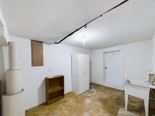 basement featuring electric panel and a textured ceiling