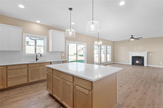 kitchen with backsplash, decorative light fixtures, sink, white cabinets, and a center island