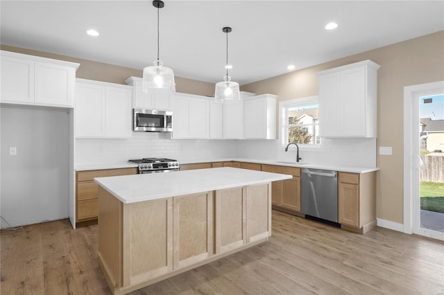 kitchen featuring stainless steel appliances, backsplash, light wood-type flooring, white cabinets, and a center island