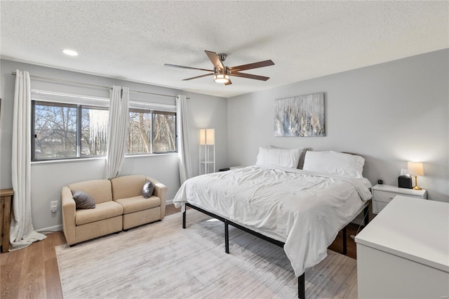 bedroom featuring a textured ceiling, ceiling fan, and light hardwood / wood-style floors