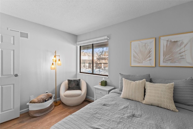 bedroom with a textured ceiling and wood-type flooring