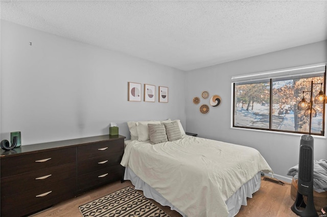 bedroom with light wood-type flooring and a textured ceiling