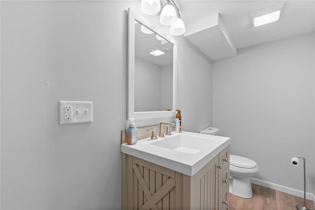 bathroom with toilet, hardwood / wood-style floors, and vanity