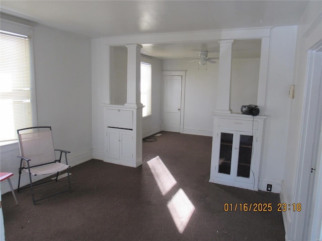 interior space with ceiling fan, dark carpet, and ornate columns