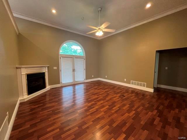 unfurnished living room featuring crown molding, ceiling fan, and dark hardwood / wood-style floors