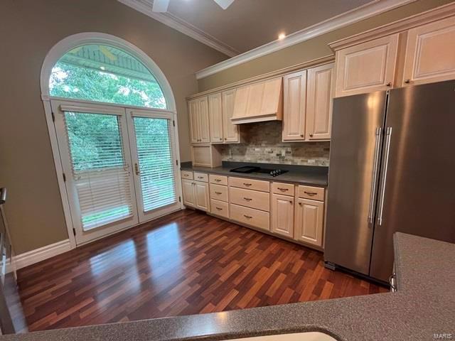 kitchen with high quality fridge, decorative backsplash, custom exhaust hood, ornamental molding, and black electric stovetop