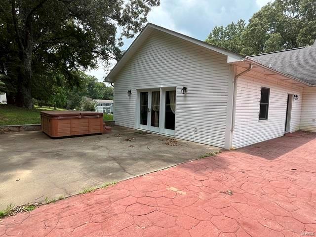 back of property featuring french doors, a hot tub, and a patio