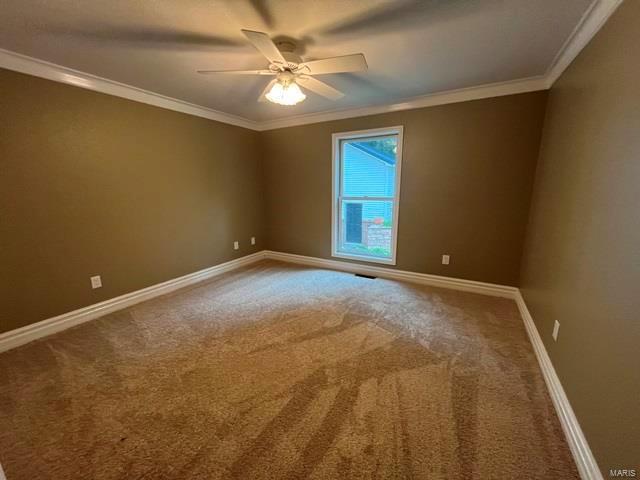 carpeted spare room featuring crown molding and ceiling fan