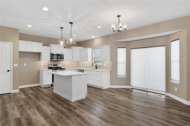 kitchen with hanging light fixtures, white cabinets, stainless steel appliances, and a kitchen island