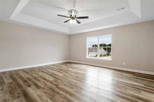 empty room featuring ceiling fan, hardwood / wood-style floors, and a raised ceiling