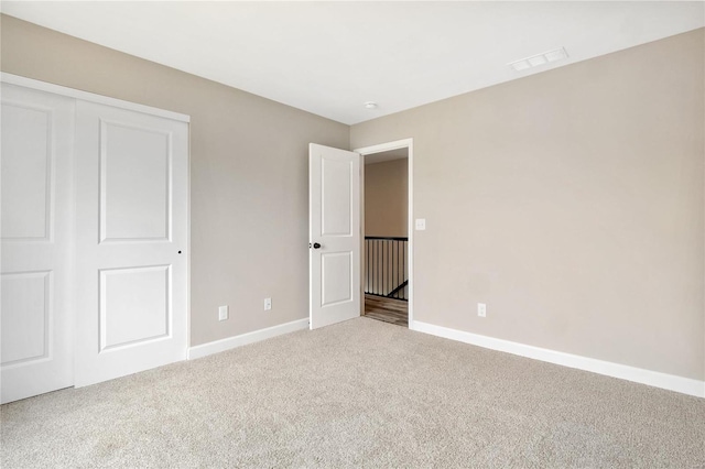 unfurnished bedroom with a closet and light colored carpet