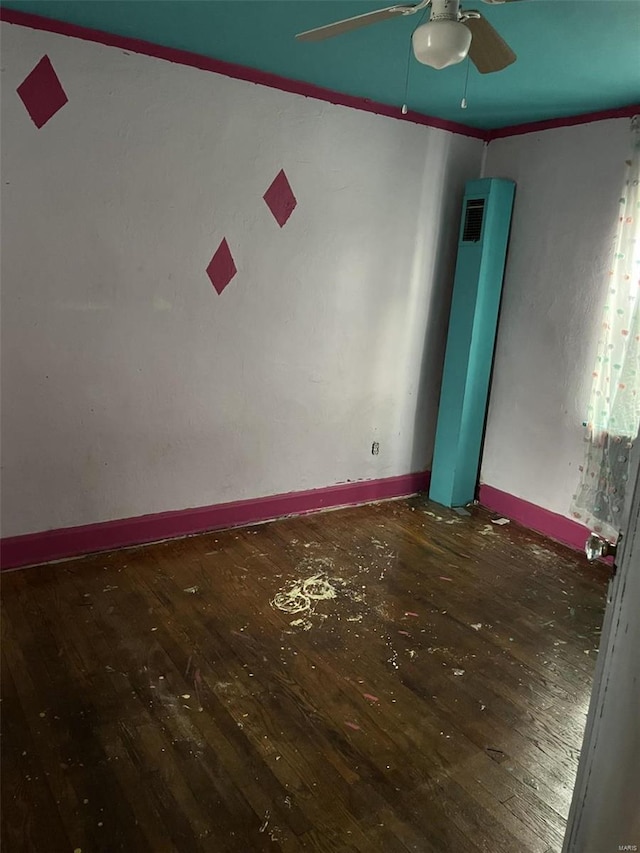 empty room with a ceiling fan, baseboards, dark wood finished floors, and crown molding