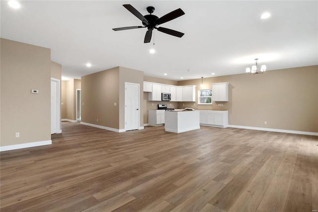 unfurnished living room featuring light wood-type flooring and ceiling fan with notable chandelier