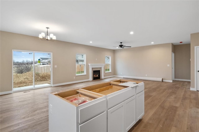 unfurnished living room with light hardwood / wood-style floors, a baseboard radiator, and ceiling fan with notable chandelier