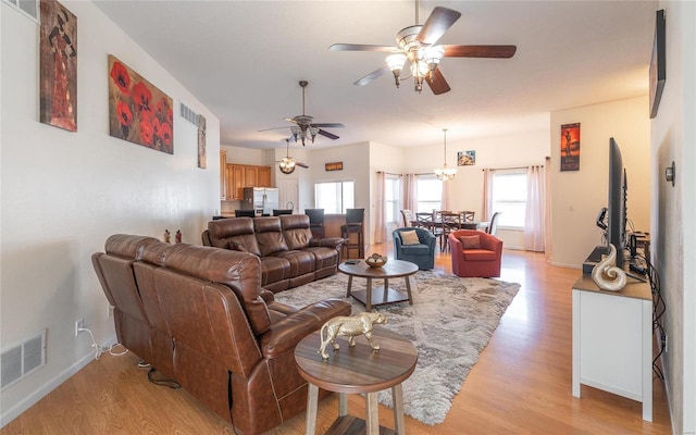 living room with ceiling fan with notable chandelier and light hardwood / wood-style flooring