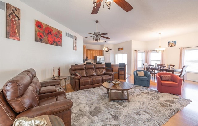 living room featuring light hardwood / wood-style floors and ceiling fan with notable chandelier