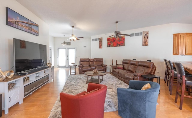 living room featuring ceiling fan, light hardwood / wood-style flooring, and a textured ceiling