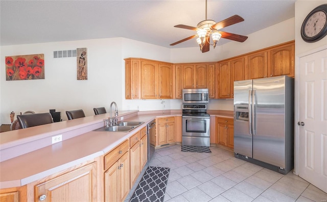 kitchen featuring ceiling fan, appliances with stainless steel finishes, sink, light tile patterned flooring, and a kitchen bar