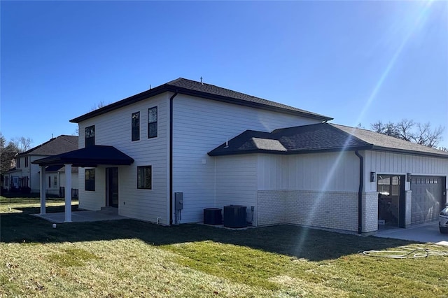 rear view of house with a lawn, cooling unit, and a garage