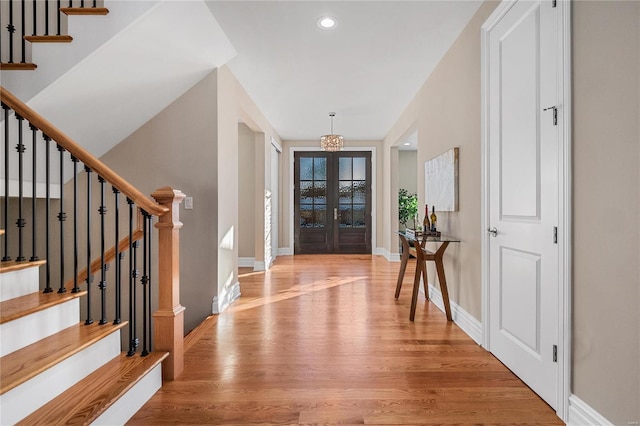 foyer entrance with french doors, a notable chandelier, and light hardwood / wood-style flooring