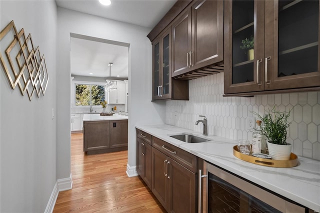 kitchen featuring light stone counters, sink, dark brown cabinetry, and light hardwood / wood-style flooring