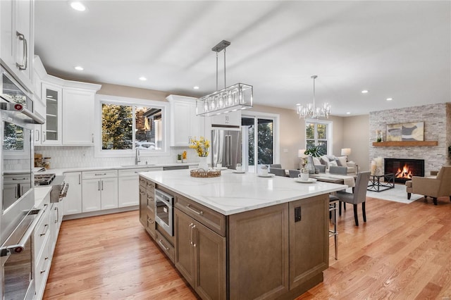 kitchen with white cabinetry, a center island, stainless steel appliances, and a stone fireplace