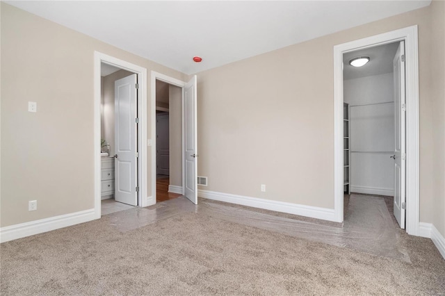 unfurnished bedroom featuring light carpet and ensuite bathroom